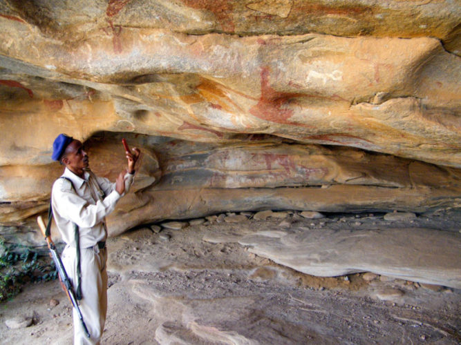 Armed guard taking a photo of the cave paintings at Laas Geel in Somaliland