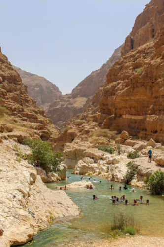 People swimming and cooling off in the river in Wadi Shab canyon