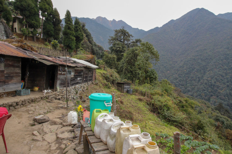 Bakhim teahouse in Sikkim with a row of plastic jerry cans and forested mountains beyond
