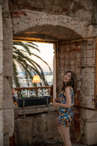 Woman-smiling-next-to-an-ancient-doorway-with-a-beautiful-view