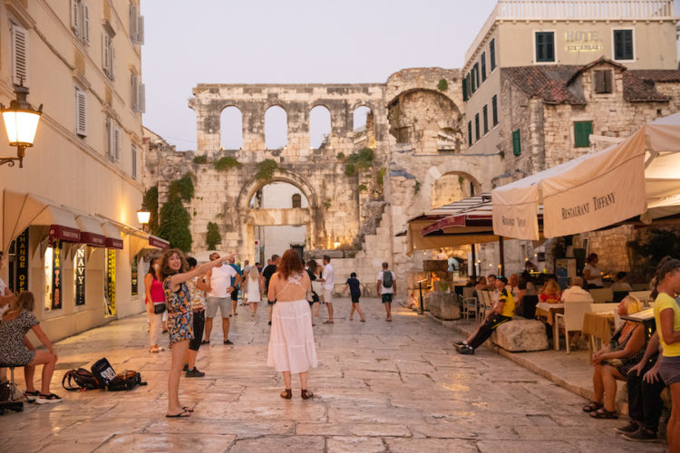 People walking through the streets of Split's old town with roman ruins, restaurants, cafes, and shops