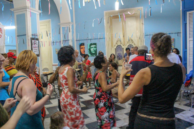 People dancing indoors in a building with blue walls and portraits of che guevara on the wall at a spontaneous dance party in Trinidad