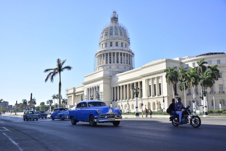 El-Capitolio-building-with-blue-vintage-cars-in-Havana-Cuba