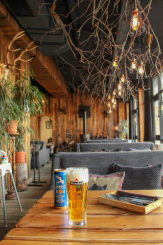 Large glass of beer with a beer can on a table in a wood-panelled restaurant in shymbulak