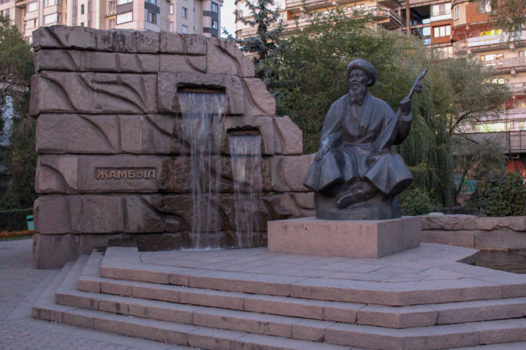 Sculpture of a traditional Kazakh musician sitting next to a water feature in Almaty