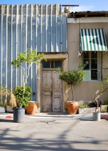 Quirky-buildings-with-corrugated-metal-wall-and-old-door-and-potted-plants-in-the-Neve-Tzedek-district-of-Tel-Aviv