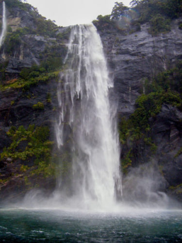 Waterfall crashing down a cliff into the sea in Milford Sound