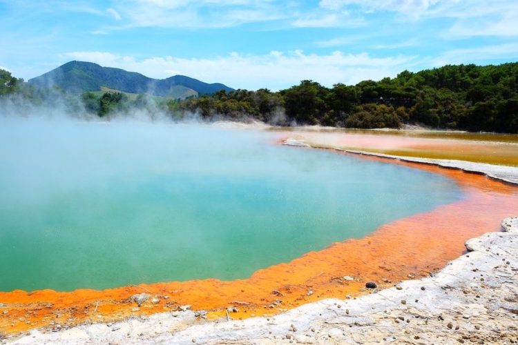 Steaming-geothermal-pool-in-rotorua-with-a-ring-of-orange-minerals-around-the-edge
