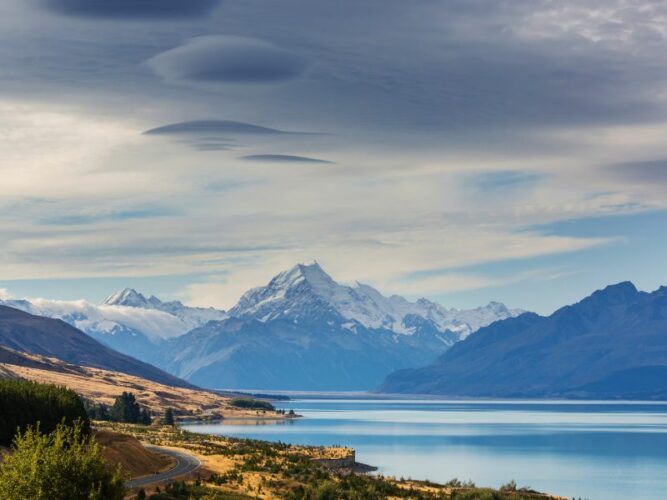 Majestic view of the snow-capped Southern Alps and a lake with unusual cloud formations in the sky