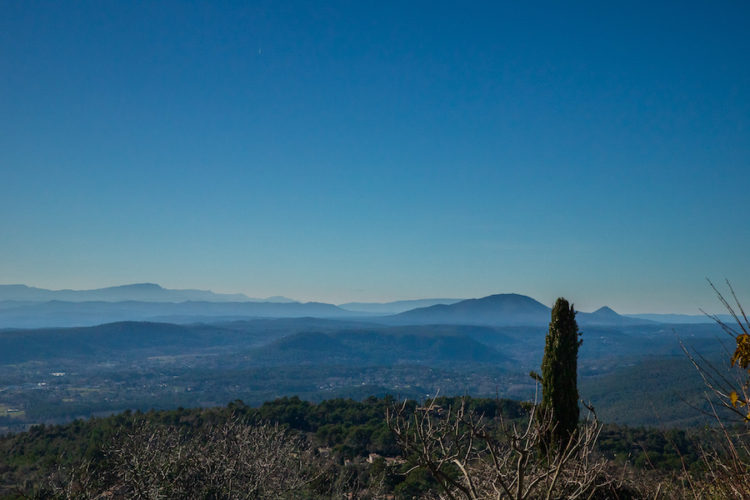 Blue skies and picturesque countryside with hazy mountains on a hiking trail near Tourtour