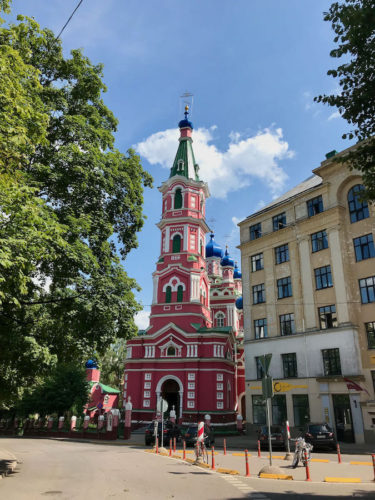Colourful church in Riga with red walls and tower and blue domes and a green spire