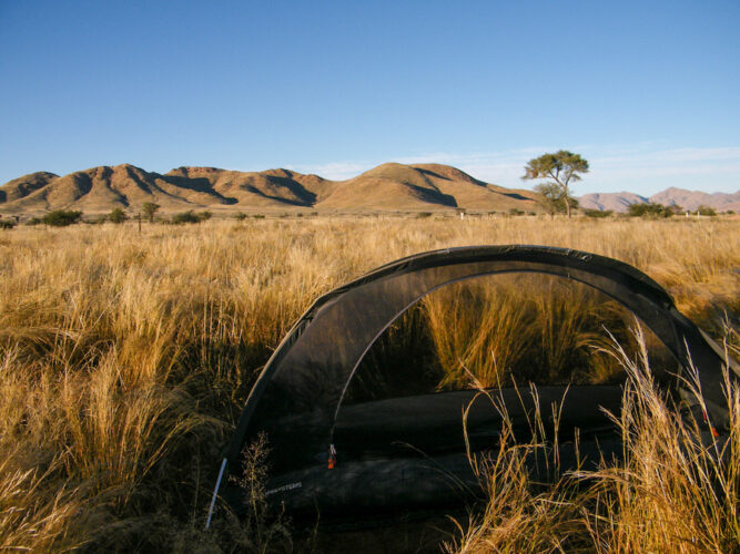 My free-standing mosquito net tent pitched in tall grass in the wilderness in Namibia