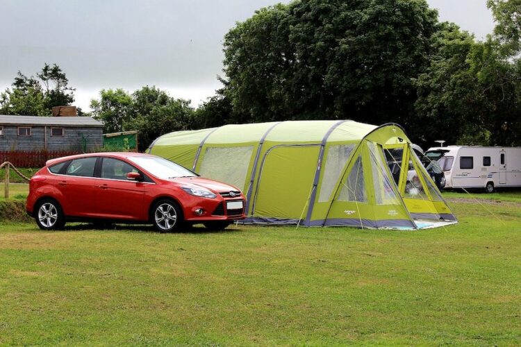 Large festival tent pitched next to a red car