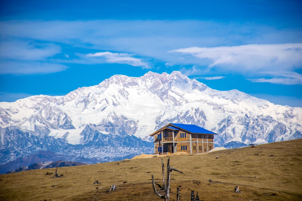 One-lonely-building-on-the-edge-of-Sandakphu-hill-station-in-india-with-towering-snow-covered-mountains-behind