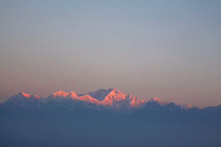 The first rays of light at sunrise illuminating the snowy peaks of Kangchenjunga mountain as viewed from Tiger Hill near Darjeeling