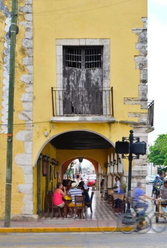 Yellow colonial building with a covered patio next to the street in Valladolid