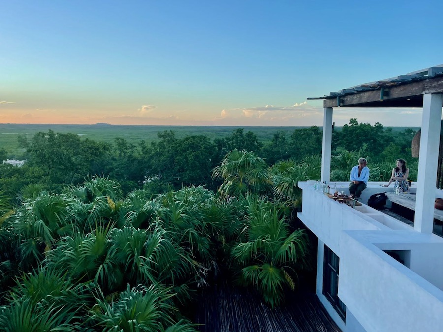 Two people talking on a beautiful raised terrace with views over the jungle in the Yucatan