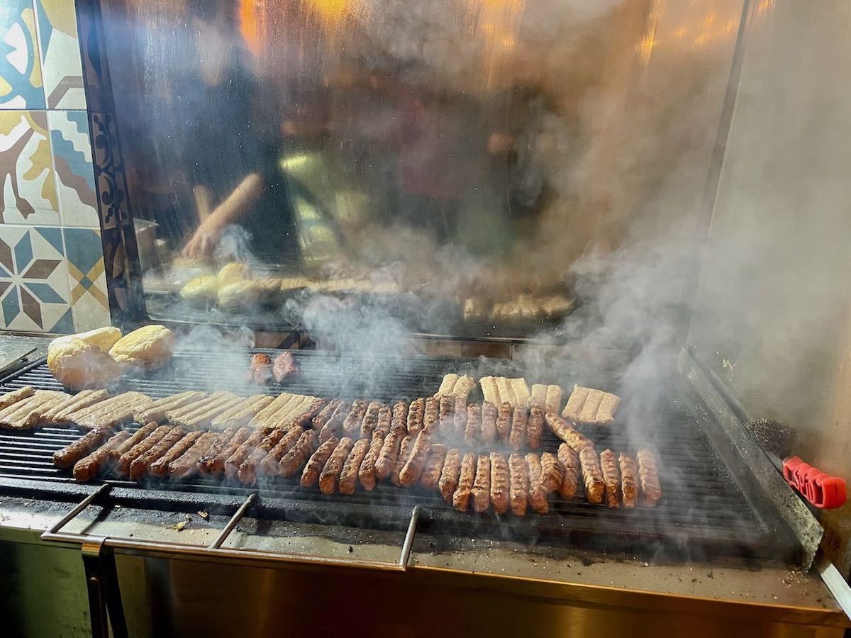Qoftes (koftas) cooking on a grill at a zgara in Tirana