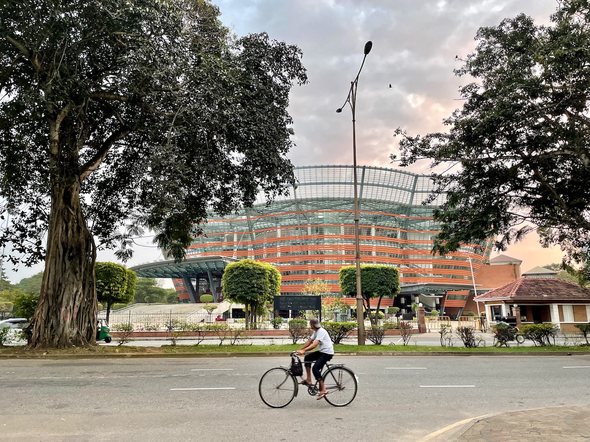 cyclist on the road with the Colombo National Performing Arts Theatre in the background