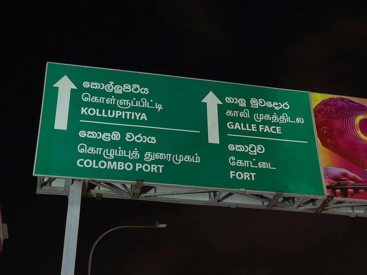 green road sign in downtown colombo pointing to colombo port, galle face, and fort