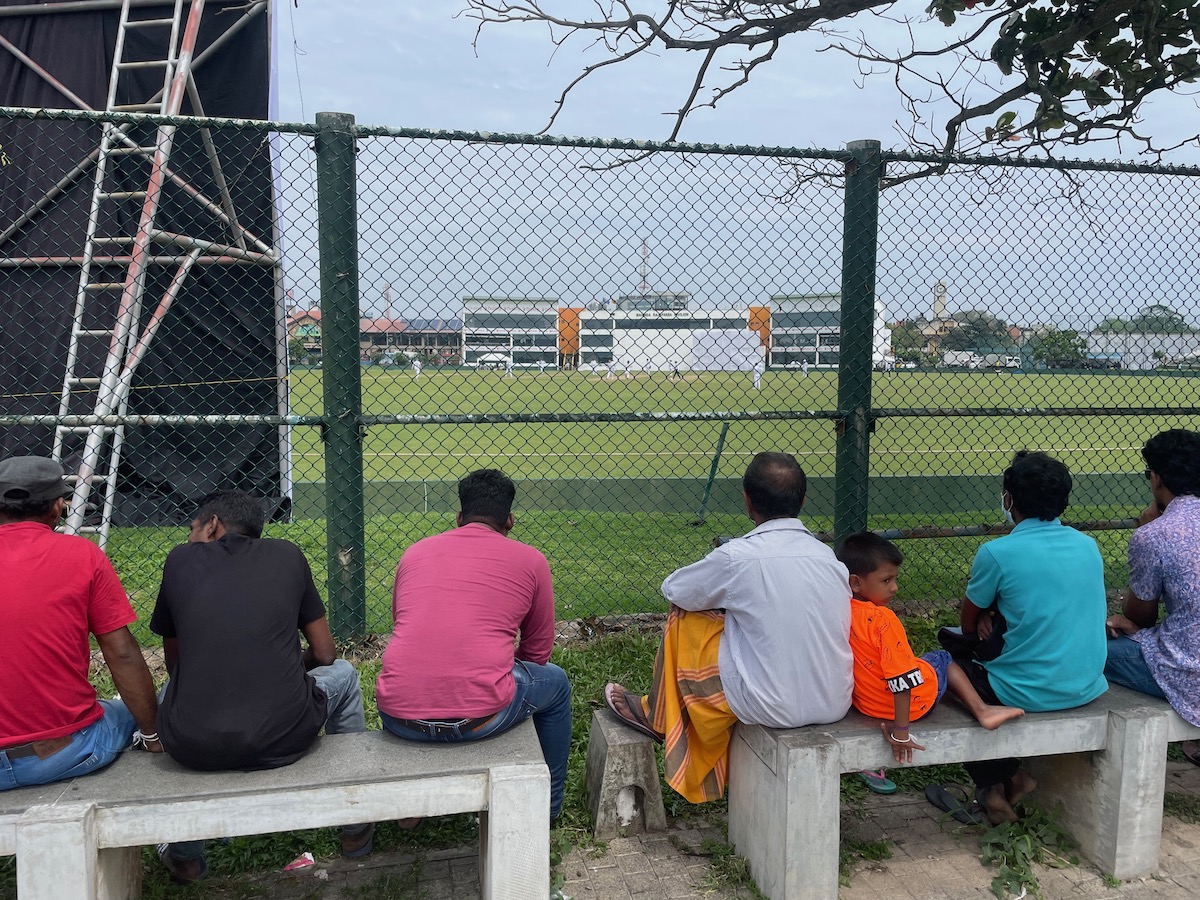men sat outside galle cricket stadium watching a cricket match