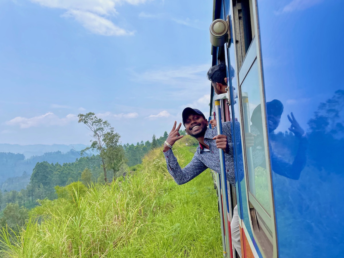 sri-lankan-man-grinning-while-leaning-out-of-the-door-of-a-train