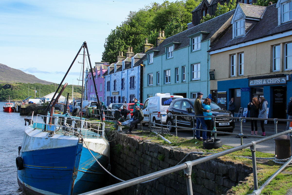 Pastel coloured cottages and a boat moored up in Portree