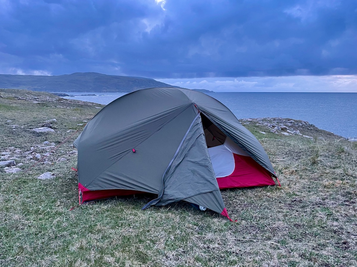 Tent camping on a lonely clifftop with Cape Wrath visible beyond taken in the twilight at dusk