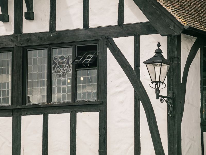 close up view of a black and white tudor building with an original window and a lamp