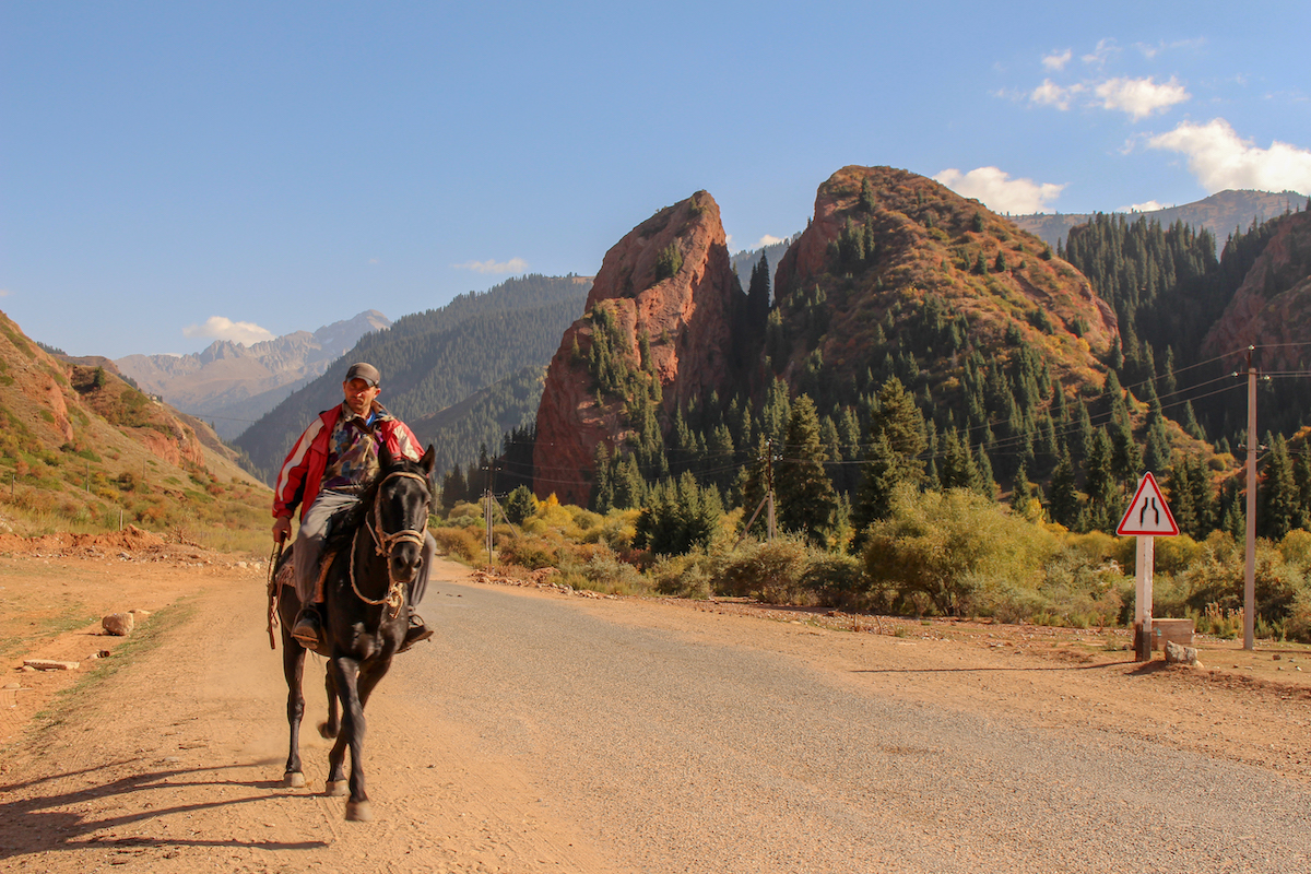 man-on-horseback-riding-along-the-road-near-jeti-oguz