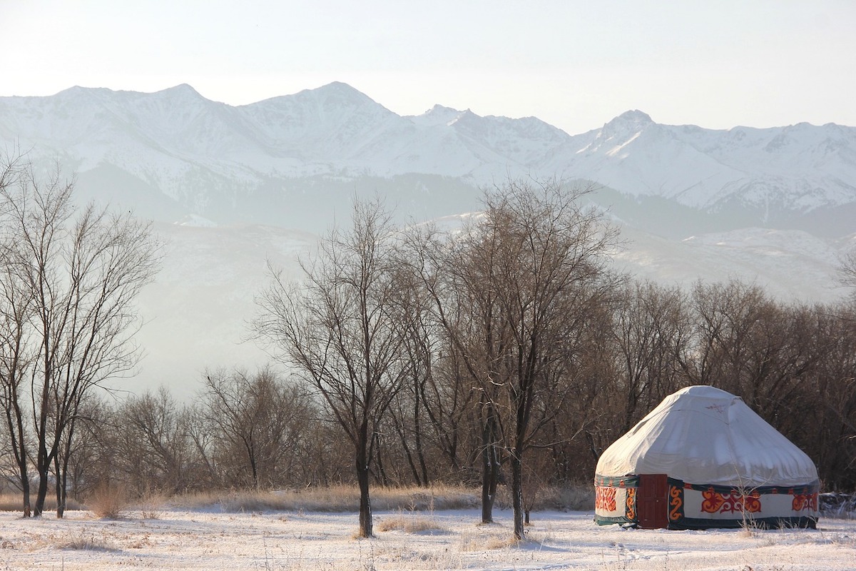 traditional nomadic yurt in the snow with mountains beyond in kazakhstan