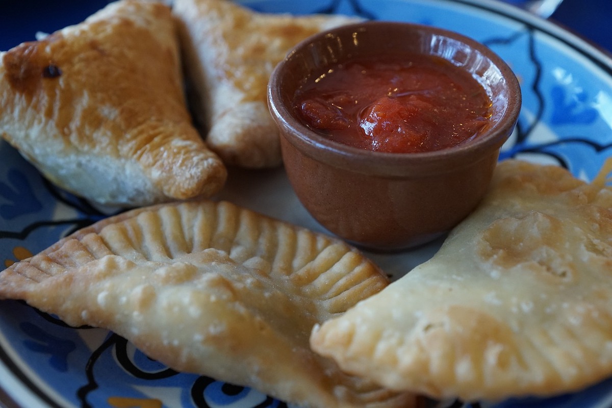 traditional kazakh fried dumplings with a pot of red spicy dipping sauce