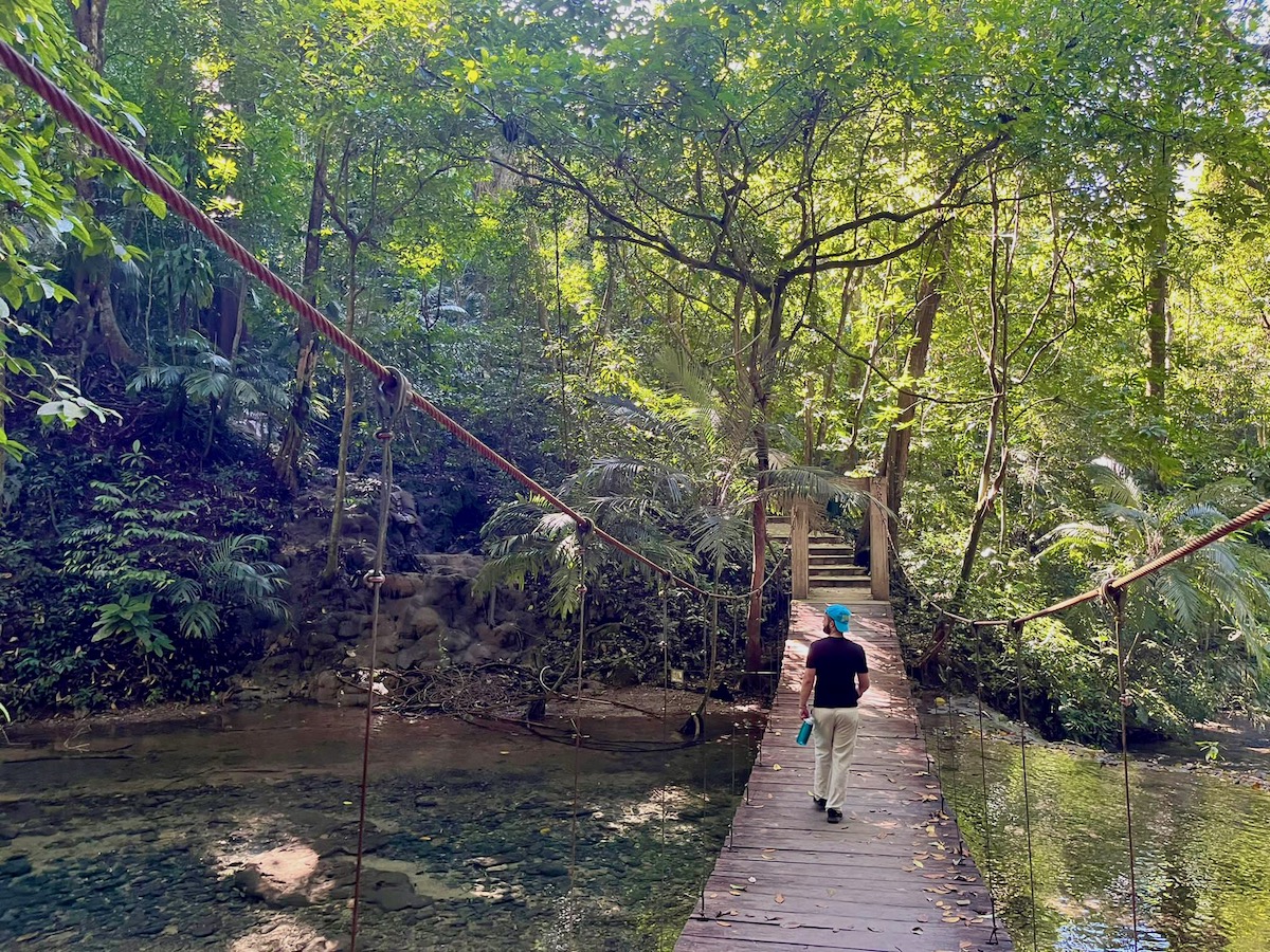 alex tiffany walking over a suspension bridge in the jungle in chiapas mexico