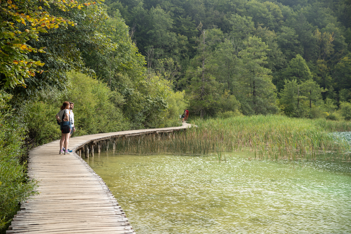 two people walking on a boardwalk in plitvice lakes national park croatia