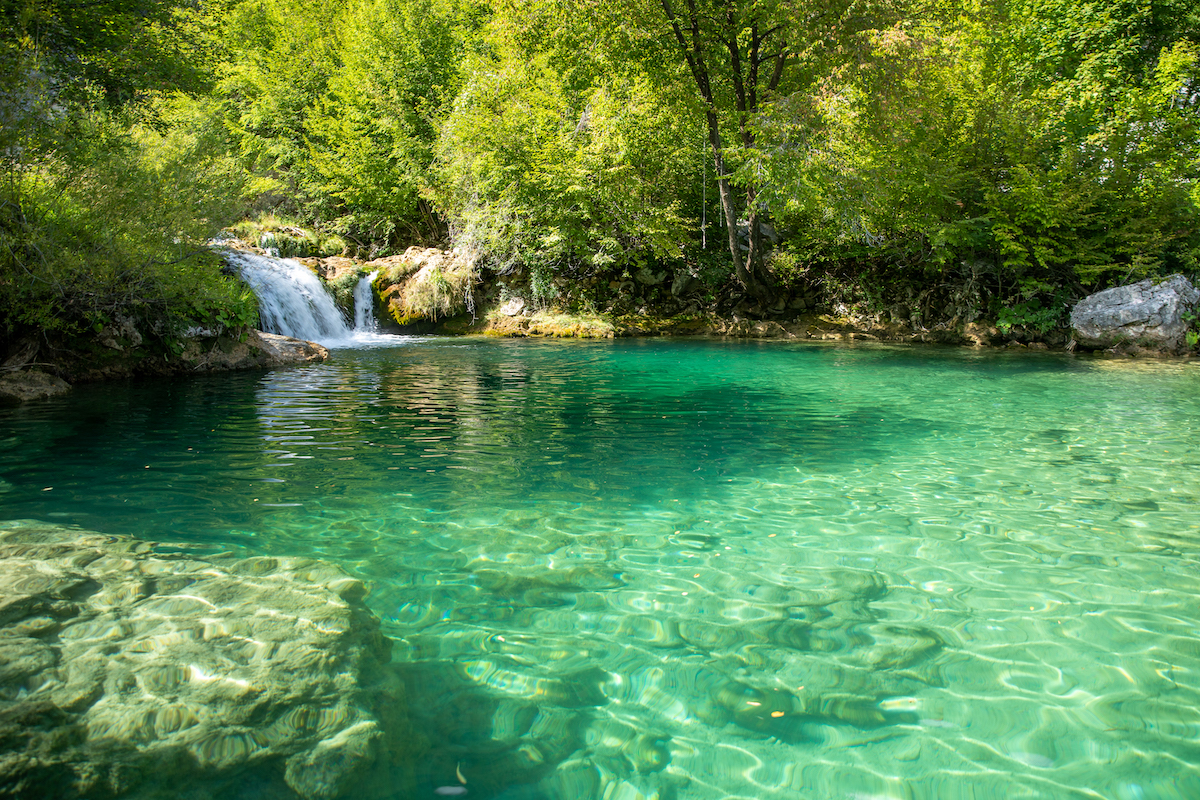 natural pool with waterfall and turquoise water near plitvice lakes