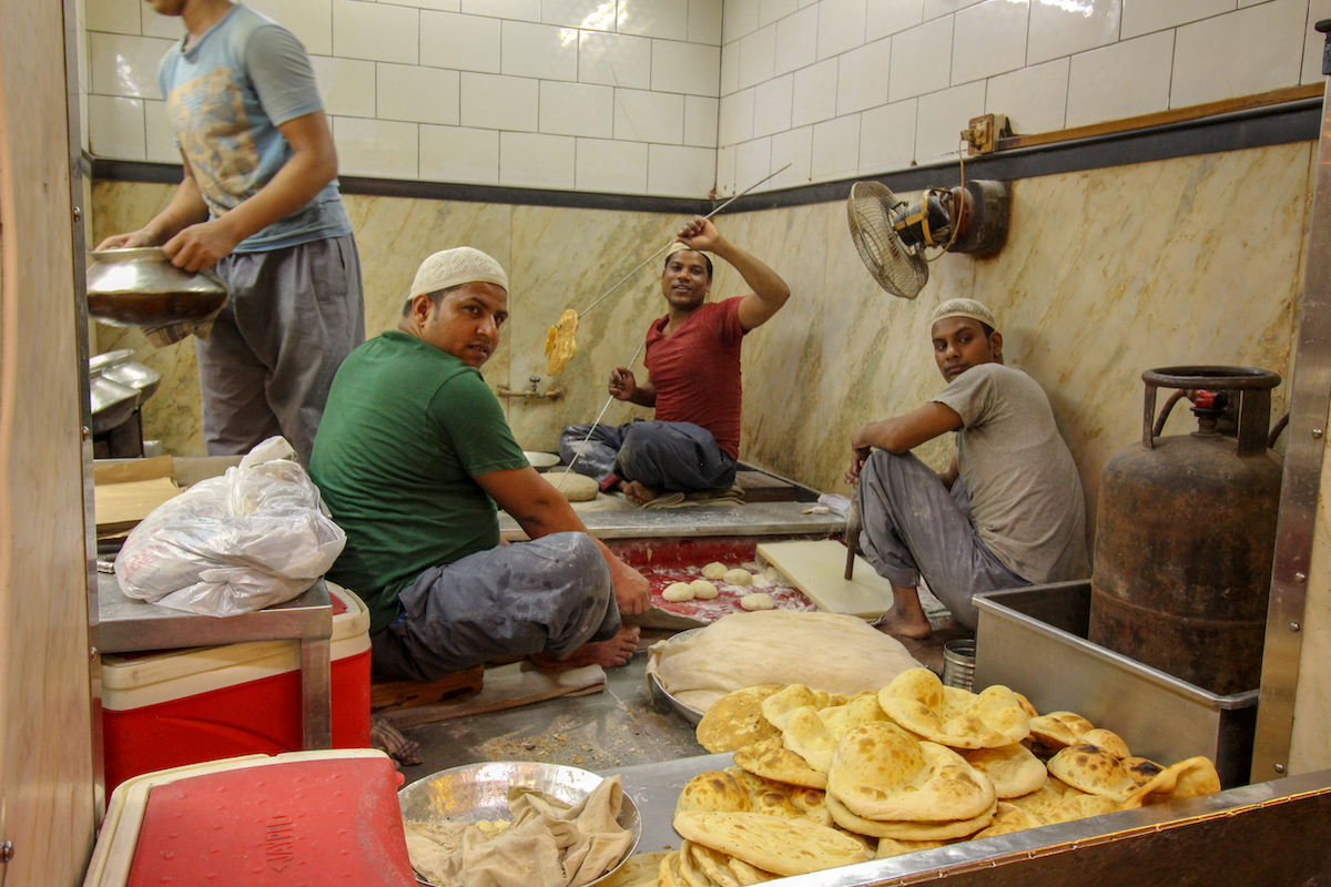 men making traditional naan bread in a restaurant in delhi