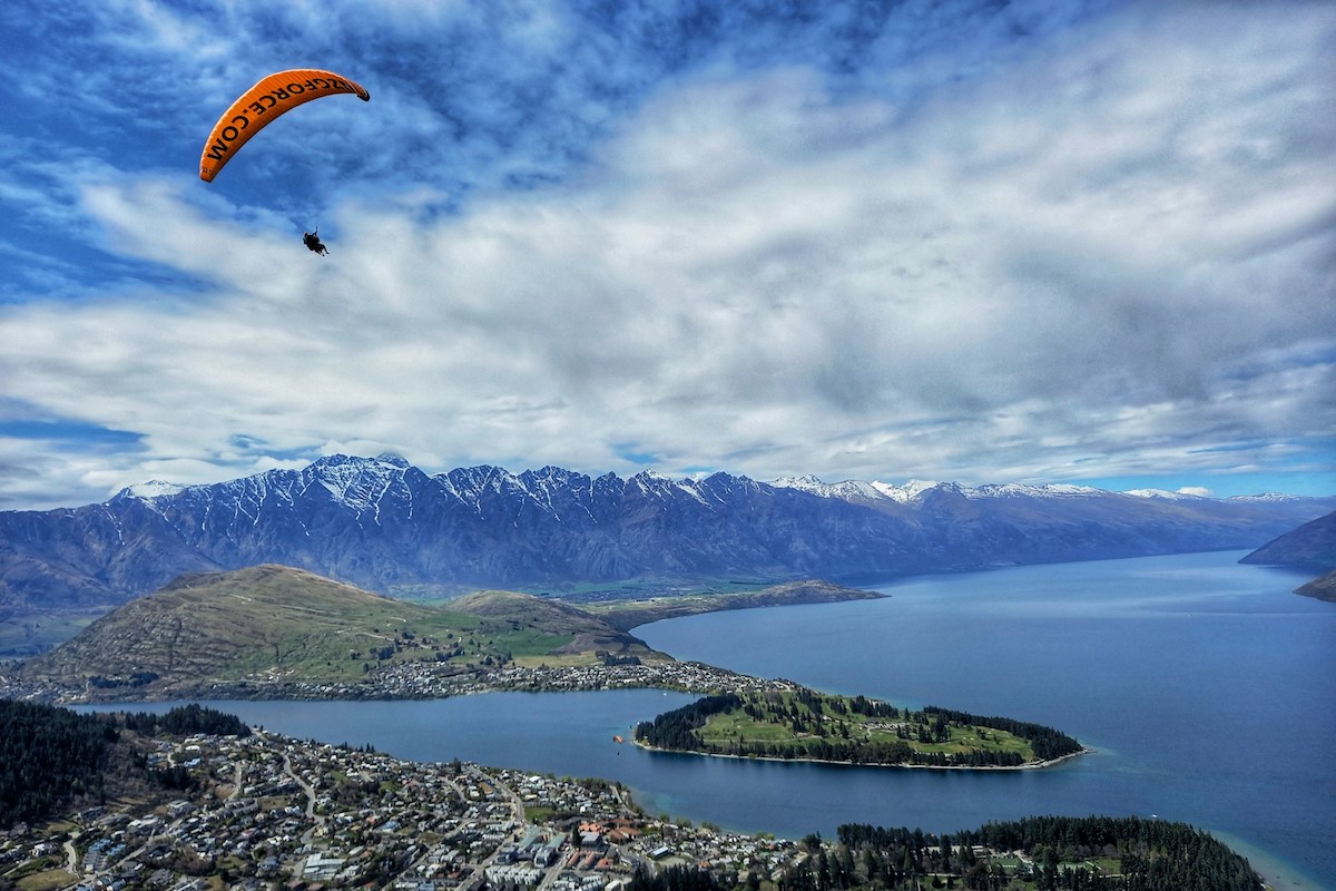 paraglider flying above queenstown in south island of new zealand