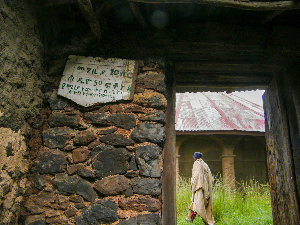 man in traditional clothes walking through an old stone monastery near lake tana ethiopia