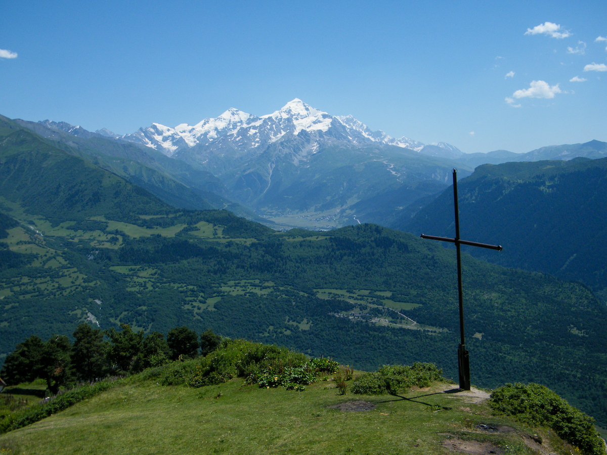 viewpoint with a cross overlooking the mestia valley in svaneti with snow capped mountains in the background