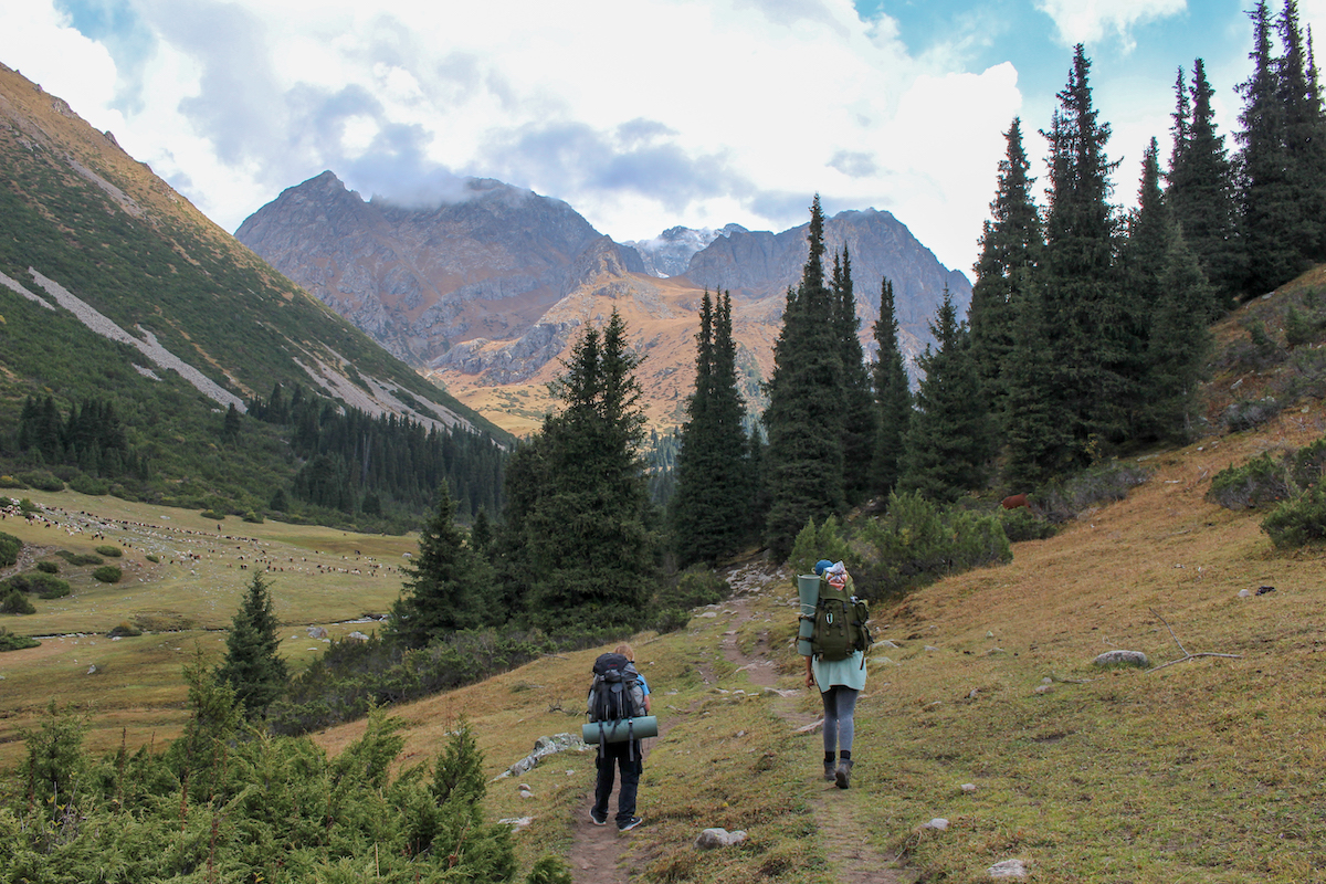 two people trekking through a valley near karakol and jeti oguz in kyrgyzstan