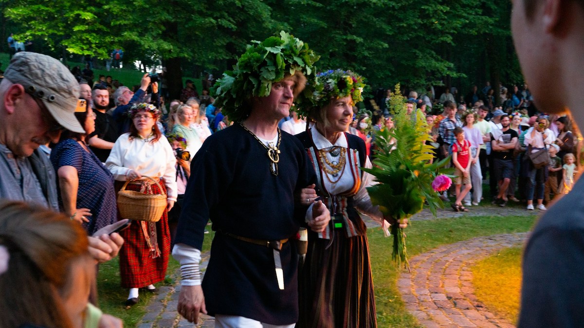 people in traditional costumes with wreaths of leaves on their heads at a ligo or midsummer celebration