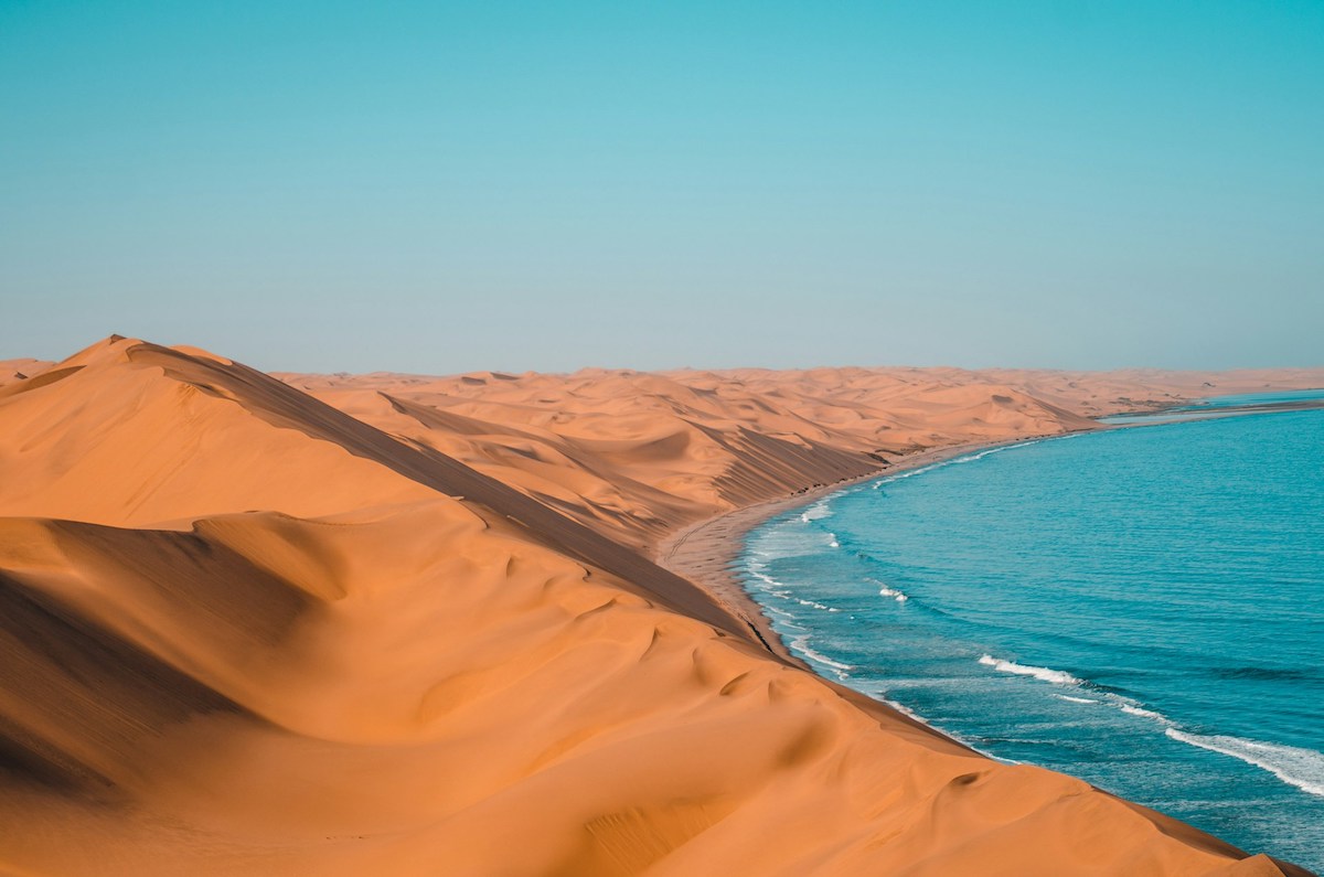 namibian coast with orange dunes giving way to blue sea