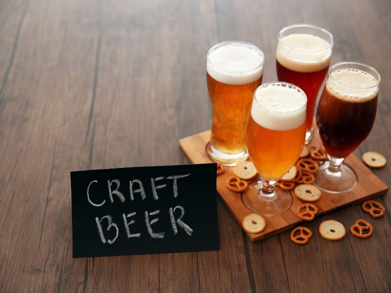 four glasses of craft beer and a board scattered with pretzels