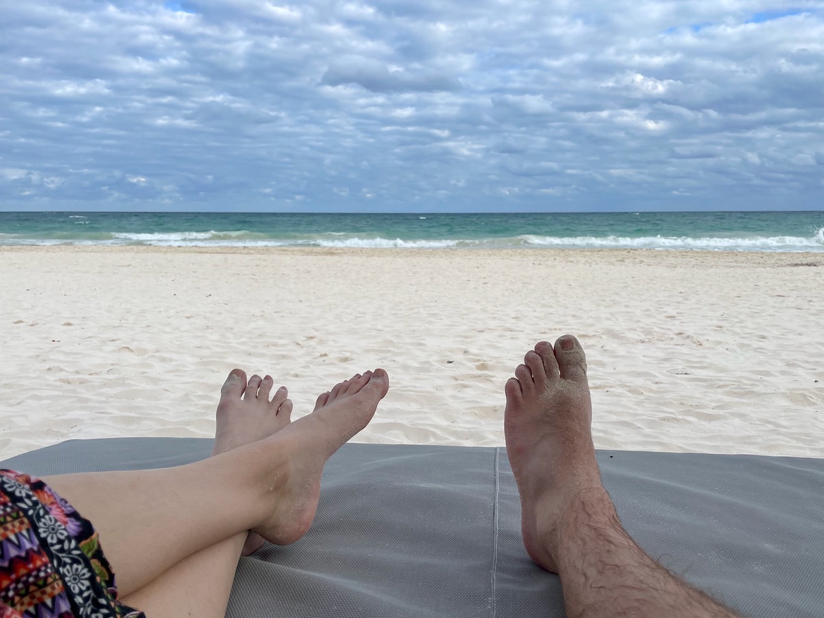 view of the beach and caribbean sea from a lounger on a beach in cozumel mexico with cloudy sky and sandy feet in the foreground