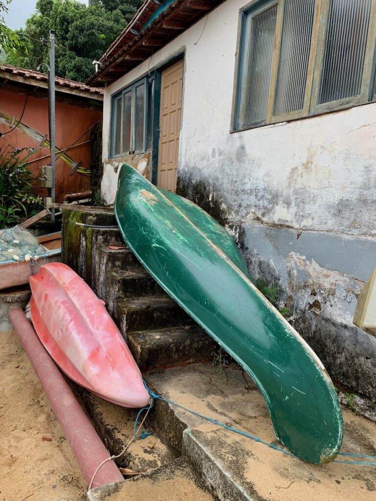 red kayak and green canoe upside down outside a pousada on ilha grande