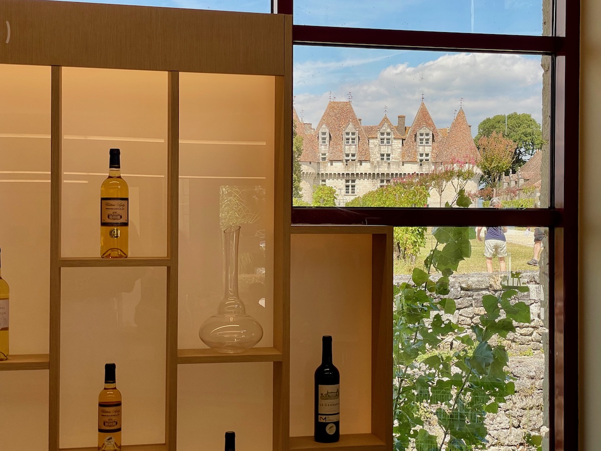 Bottles of wine displayed inside the tasting room of Chateau de Monbazillac near Bergerac with a view of the castle through a window