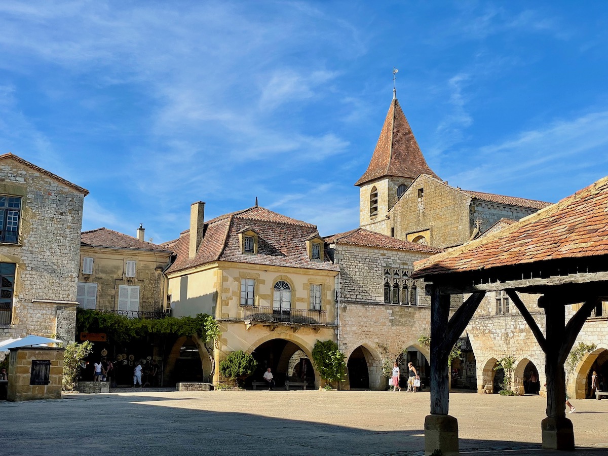 Town square of Monpazier, Dordogne with beautiful medieval stone buildings and blue skies