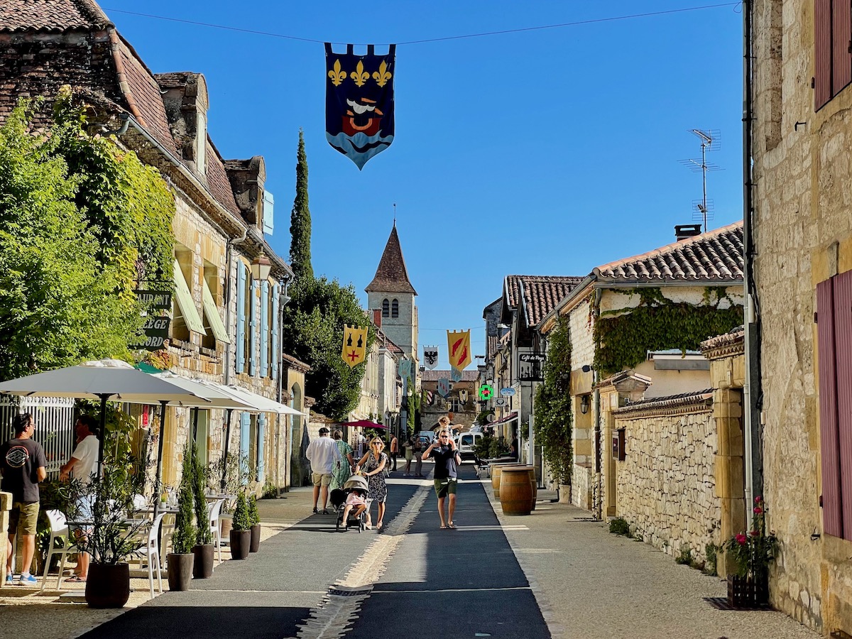 Pleasant street in Monpazier on a sunny day with people walking in the sunshine