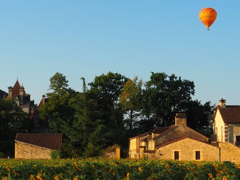 Orange hot air balloon in the sky above a picturesque southern french town