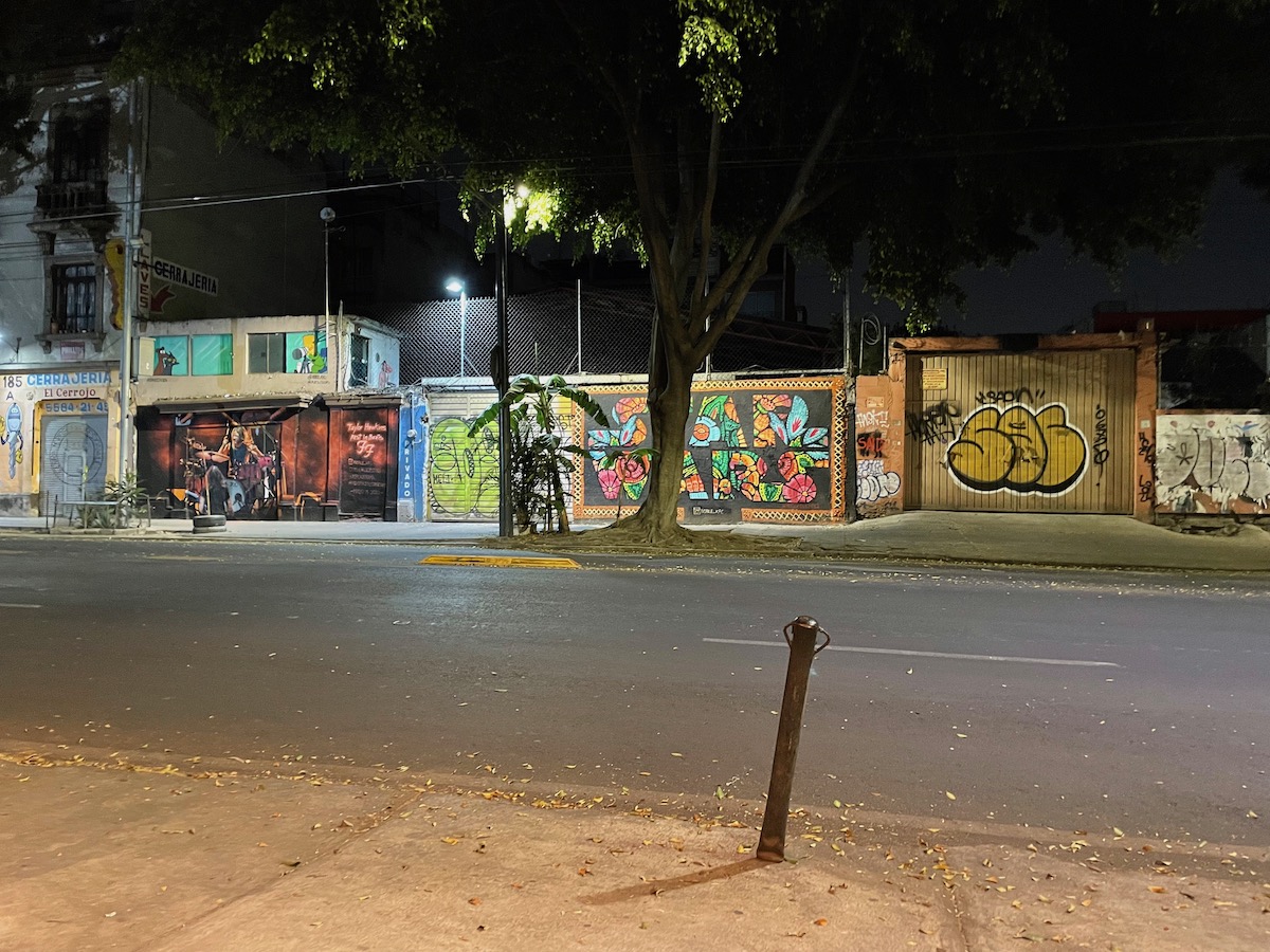 Street in Roma Norte at night with illuminated street art and graffiti